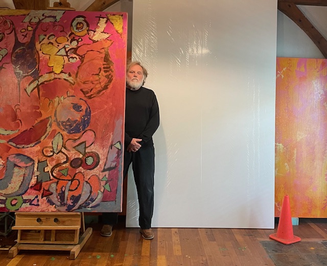 william hemmerdinger stands behind a large piece of art on canvas